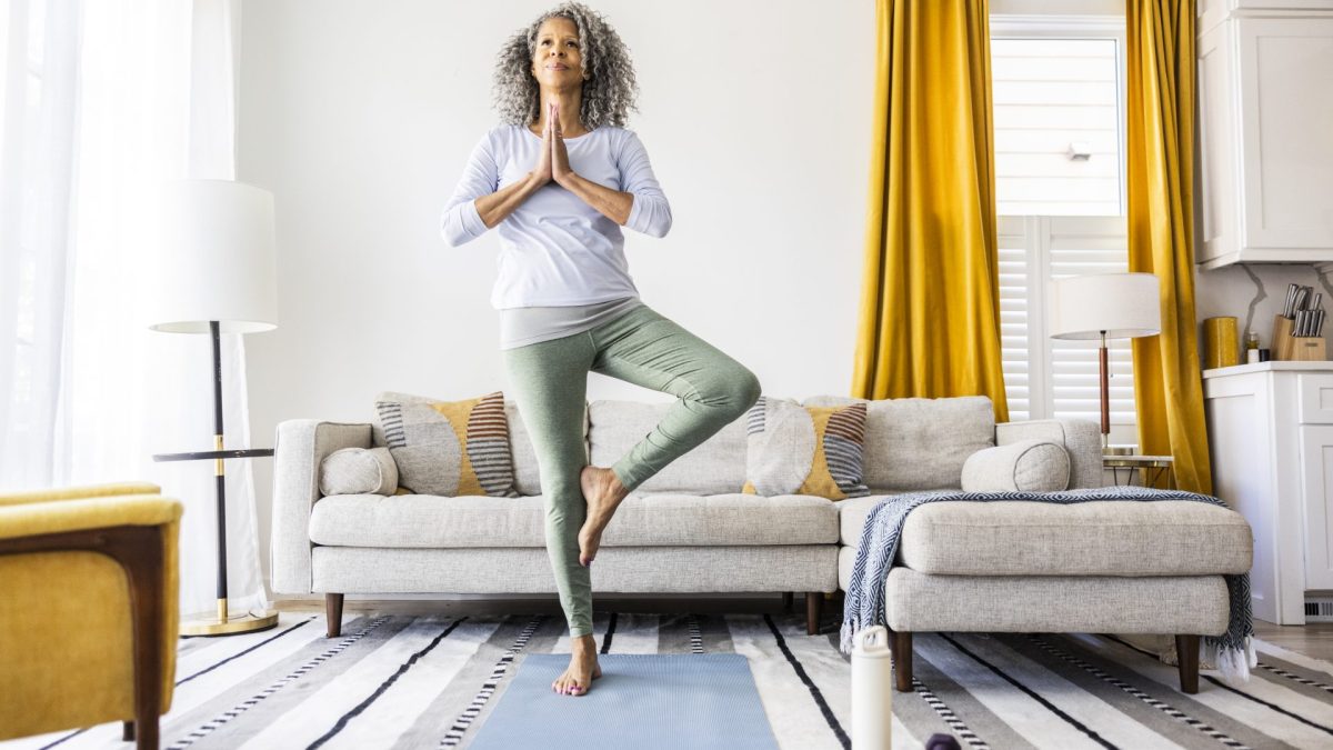 Senior woman doing yoga in living room - stock photo