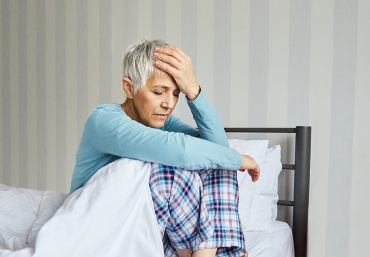Senior bed woman problem pain headache home elderly mature pain bedroom upset unhappy female caucasian adult relationship retirement old difficulty ache head sick migraine hangover sleep - stock photo