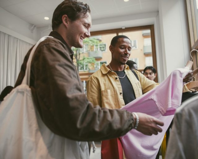 Low angle view of smiling man shopping with male friend at clothes store - stock photo