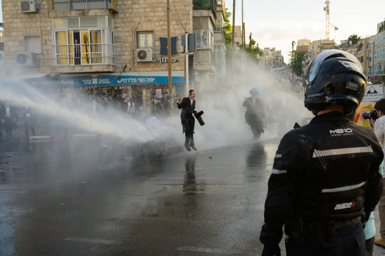 Haredi ultra-Orthodox protesters are sprayed by a police water cannon during a protest against military conscription and the arrest of yeshiva students accused of draft evasion in Jerusalem on May 28, 2026.