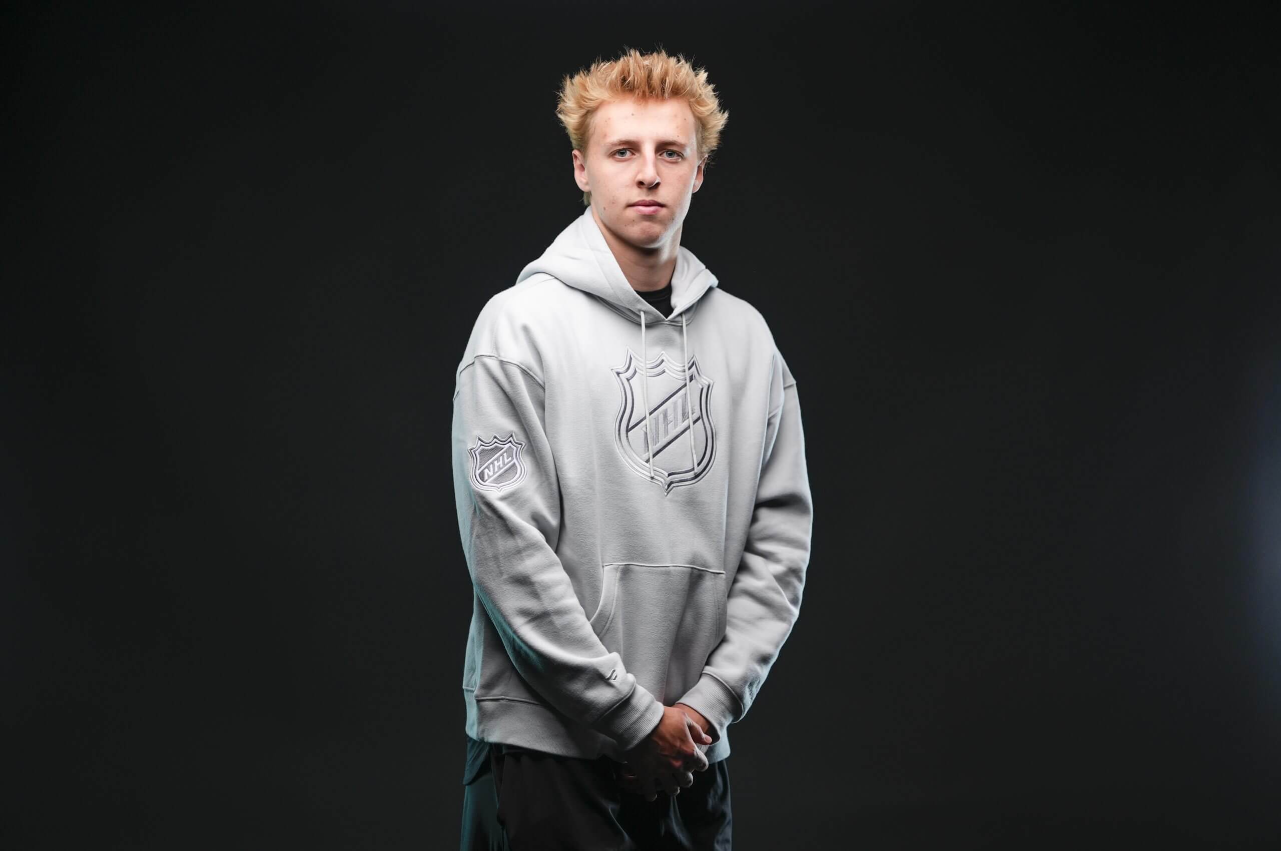 Jayden Kurtz poses in an NHL hoodie in front of a black background