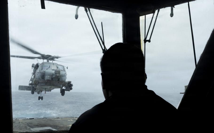 A sailor looks out a window as the helicopter takes flight.
