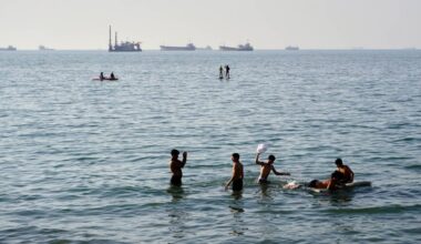 Residents swim and play in the waters of the Strait of Hormuz while cargo ships and commercial vessels lie anchored in the distance off Bandar Abbas, Iran, Wednesday, June 10, 2026.(Razieh Poudat/ISNA via AP)