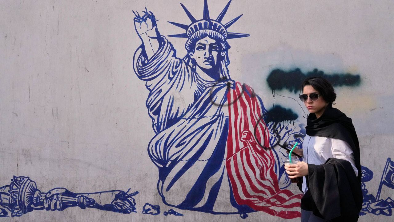 A woman walks past an anti-American mural on the wall of the former U.S. Embassy, now a museum, in Tehran, Iran, Friday, June 12, 2026. (AP Photo/Vahid Salemi)