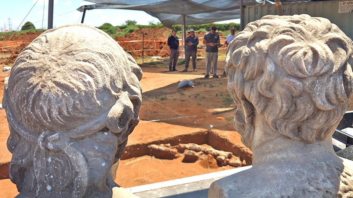 Two statues facing away from excavation site
