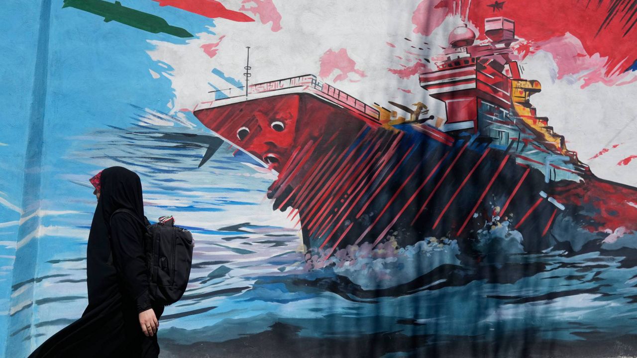 A woman walks past a mural depicting a U.S. aircraft carrier under missile attack in downtown Tehran, Iran, Monday, June 8, 2026. (AP Photo/Vahid Salemi)