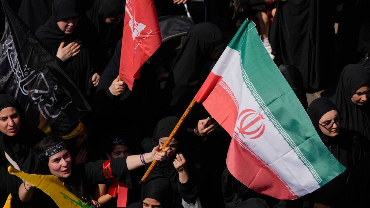 A Hezbollah supporter waves an Iranian flag, as she marches during the holy day of Ashoura that commemorates the 7th century martyrdom of the Prophet Muhammad's grandson Hussein, in Dahiyeh, Beirut's southern suburbs, Lebanon, Friday, June 26, 2026. (AP Photo/Hussein Malla)