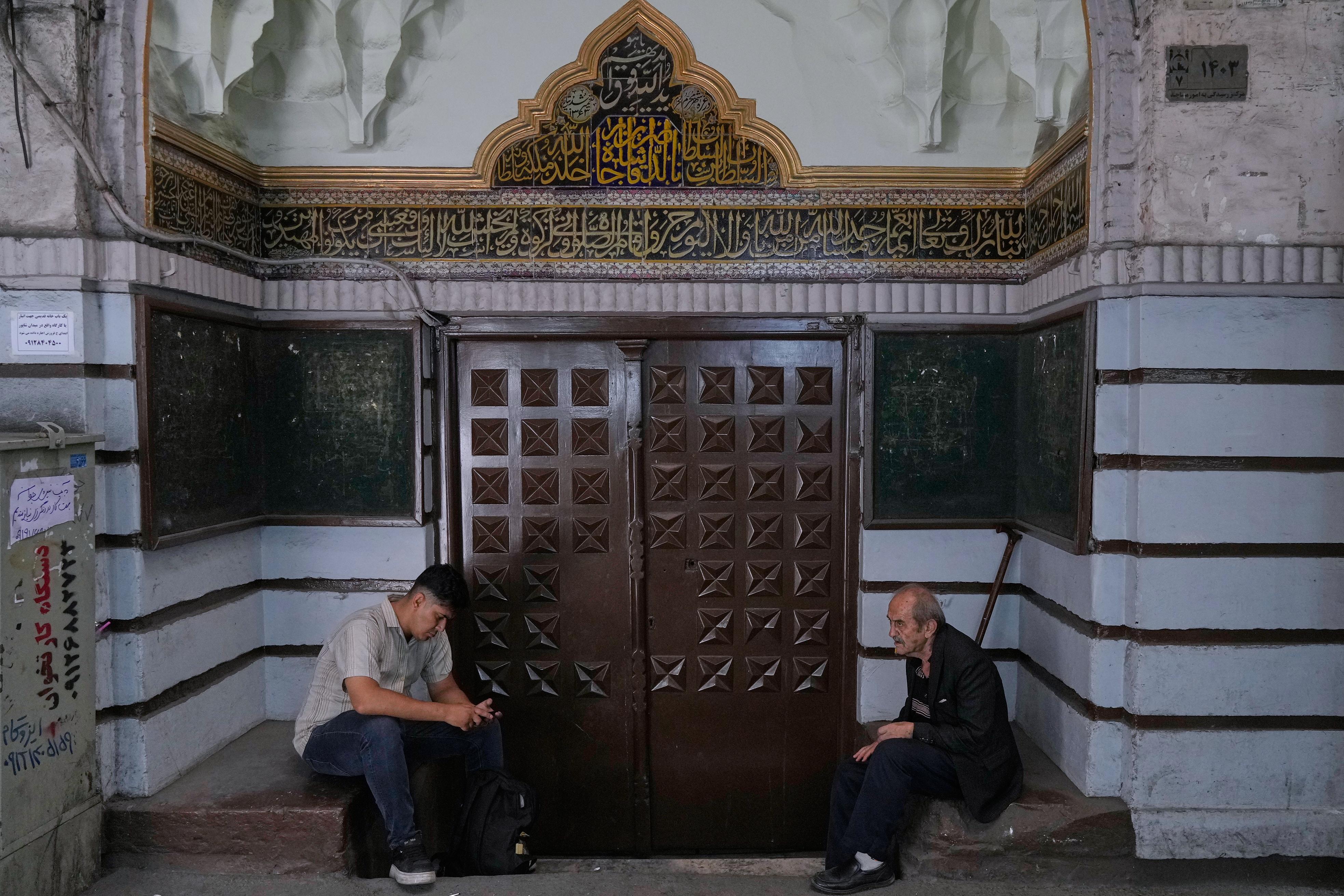Men sit at the gate of a mosque at Tehran's historic Grand Bazaar.