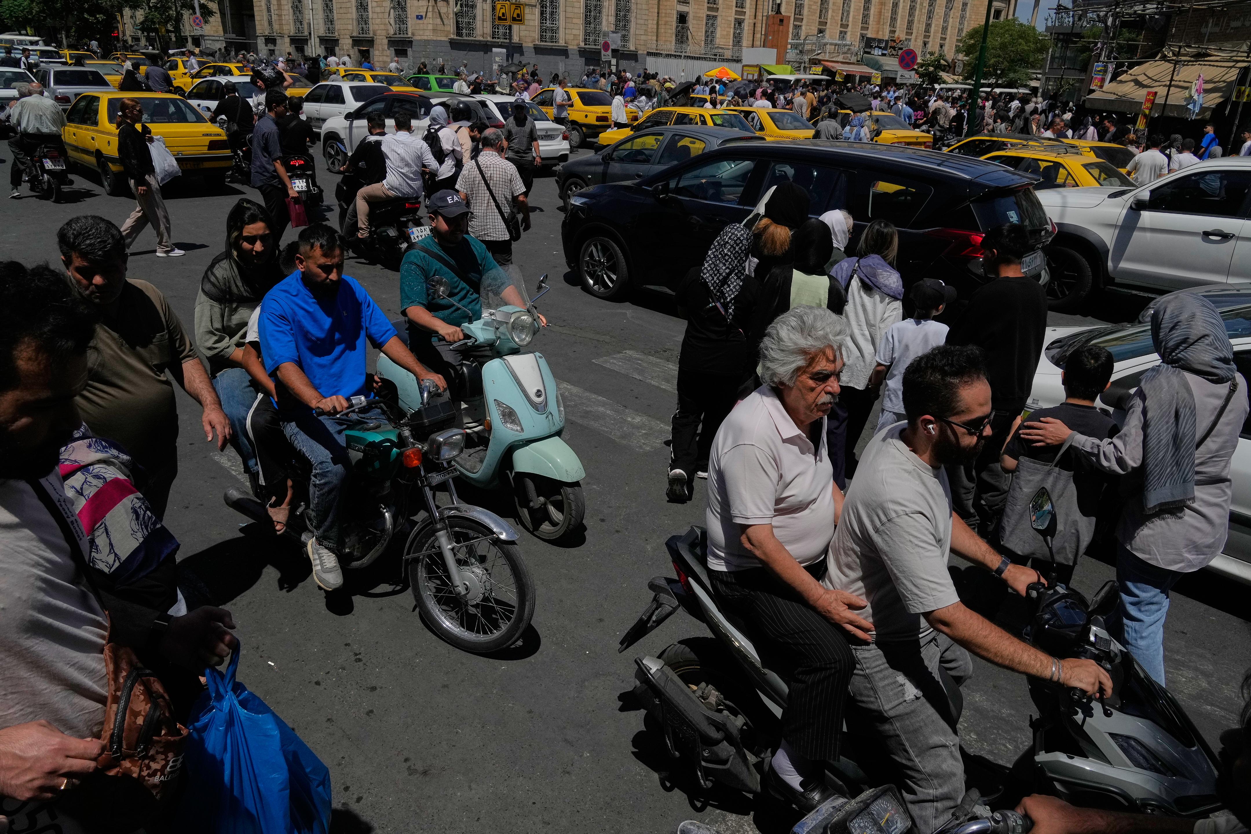 Pedestrians and vehicles cross an intersection around Tehran's Grand Bazaar.