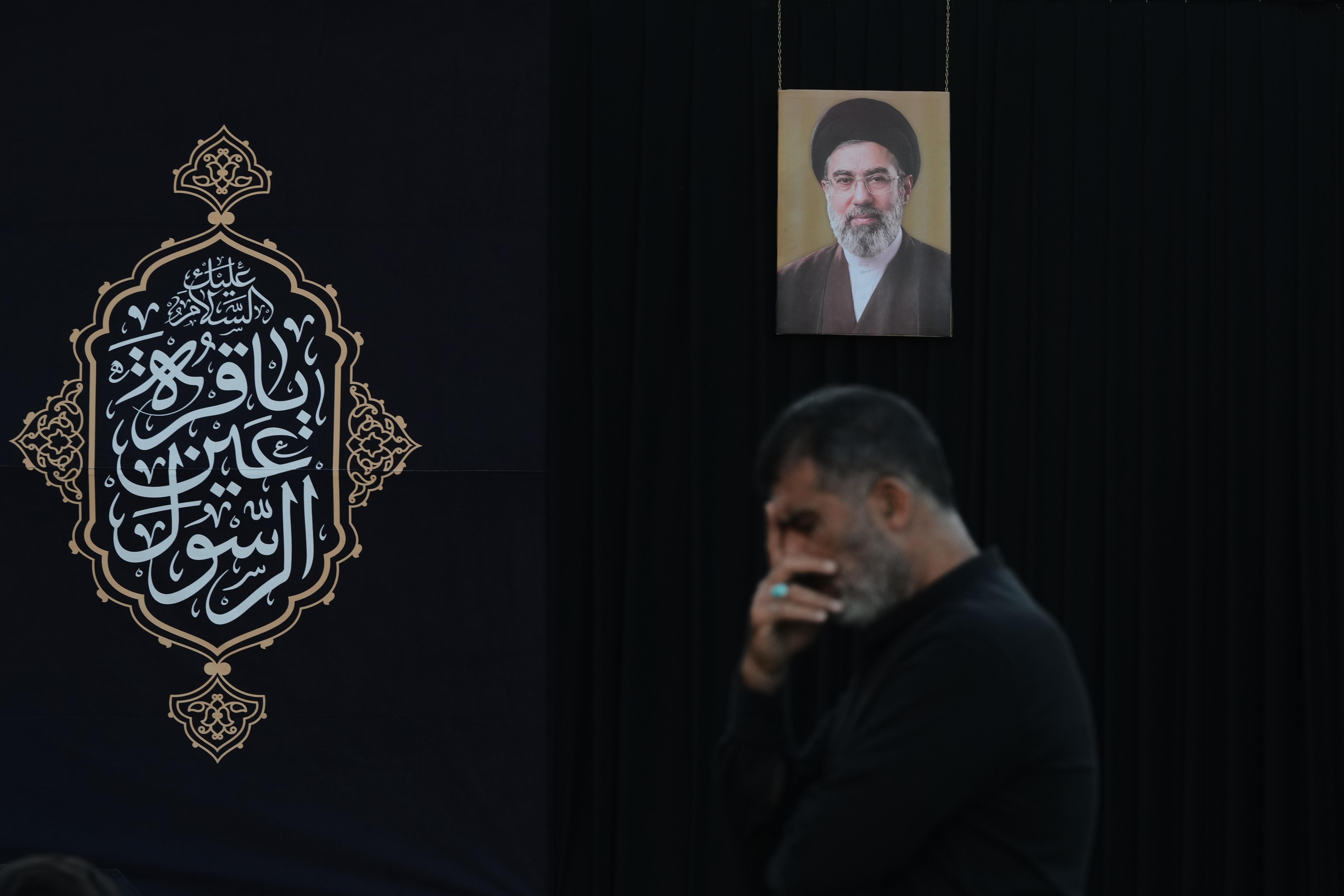 A man attends a sermon backdropped by a portrait of...