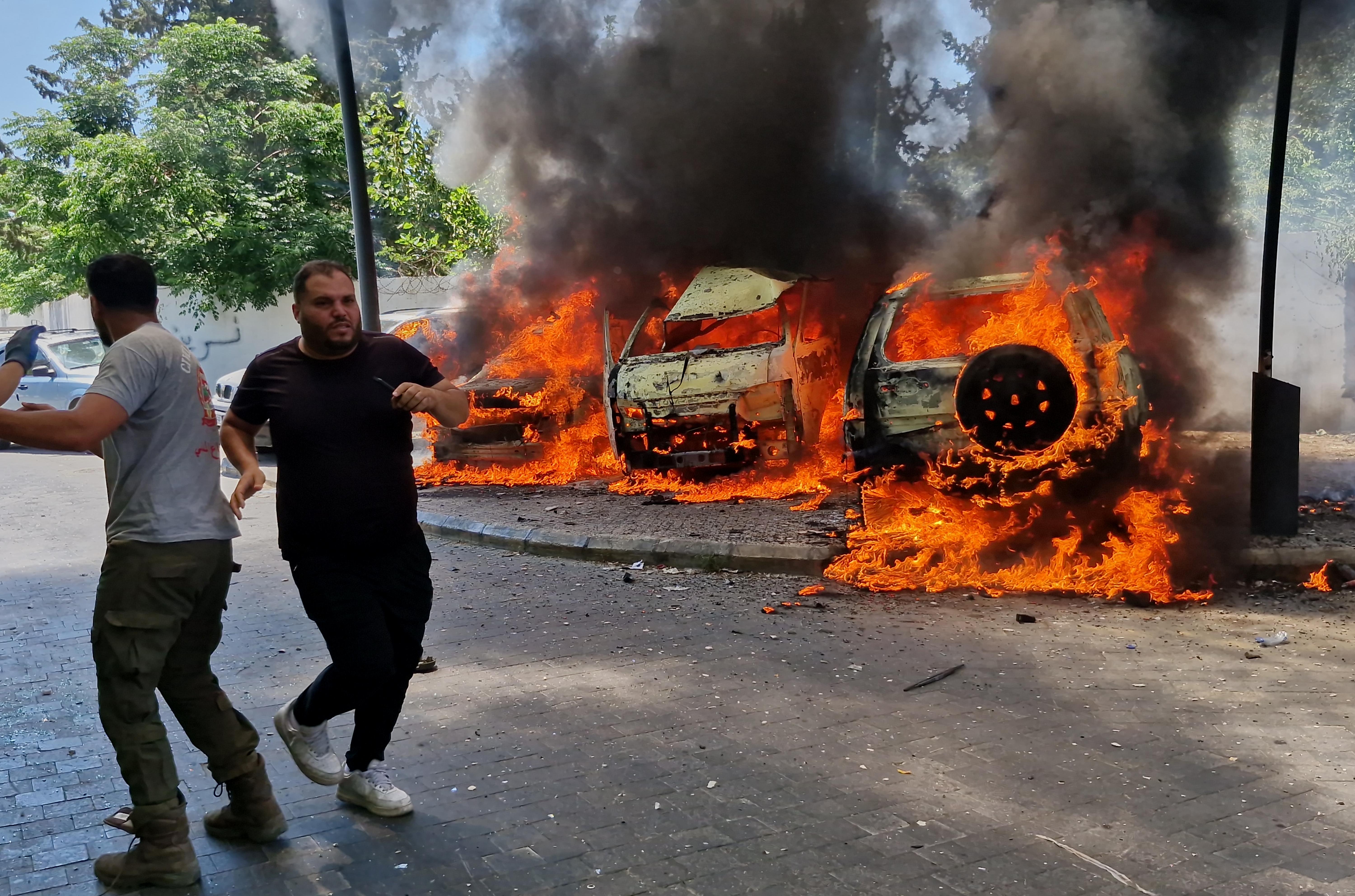 A man runs past burning cars following an Israeli airstrike in Sidon, Lebanon.