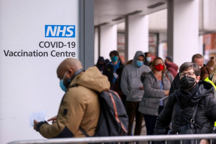Visitors queue for Covid-19 vaccinations at a National Health Service (NHS) walk-in vaccine center at Romford, U.K., on Monday, Dec. 13, 2021. Prime Minister Boris Johnson warned the U.K. is facing a "tidal wave" of omicron infections and set an end-of-year deadline for the country's booster vaccination program. Photographer: Chris Ratcliffe/Bloomberg via Getty Images
