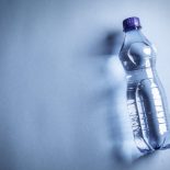 Plastic bottle with clean water on a blue background.