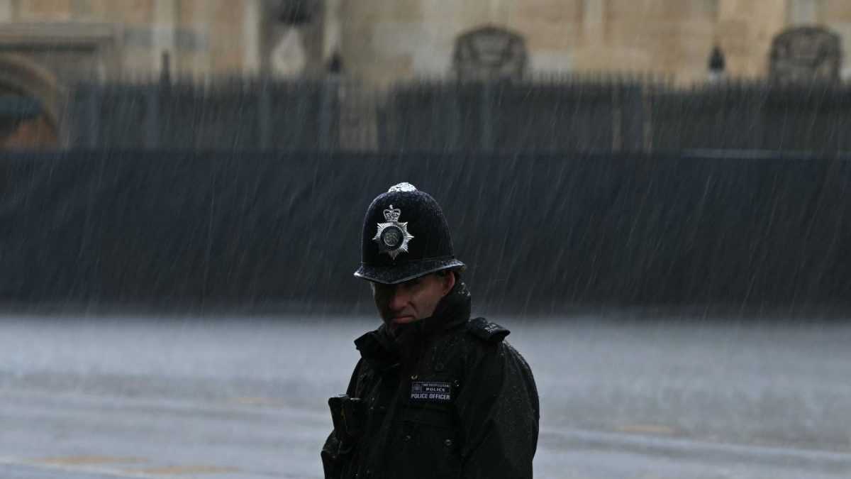 A Metropolitan Police Officer stands in the rain outside the Houses of Parliament in London on May 13, 2026, during the State Opening of Parliament. (Photo by JUSTIN TALLIS / POOL / AFP via Getty Images)