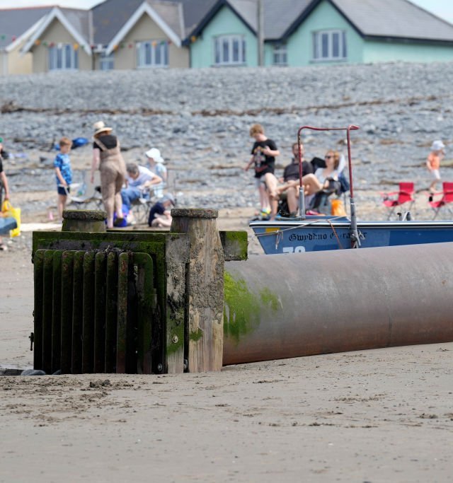 BORTH, WALES - AUGUST 10: Summer holidaymakers play and relax on Borth Beach next to a storm overflow pipe that discharges into the sea on August 10, 2023 in Borth, Wales. There were more than 80,000 sewage overflows into Welsh seas and rivers for more than 500,000 hours in 2022 Surfers reported gastric illnesses after using beaches including Borth Beach. Dwr Cymru, which is responsible for managing water across most of Wales, blames aging infrastructure and the Welsh climate of high rainfall for overflows and has recently installed 2,300 monitors to help reduce the problem. (Photo by Christopher Furlong/Getty Images)