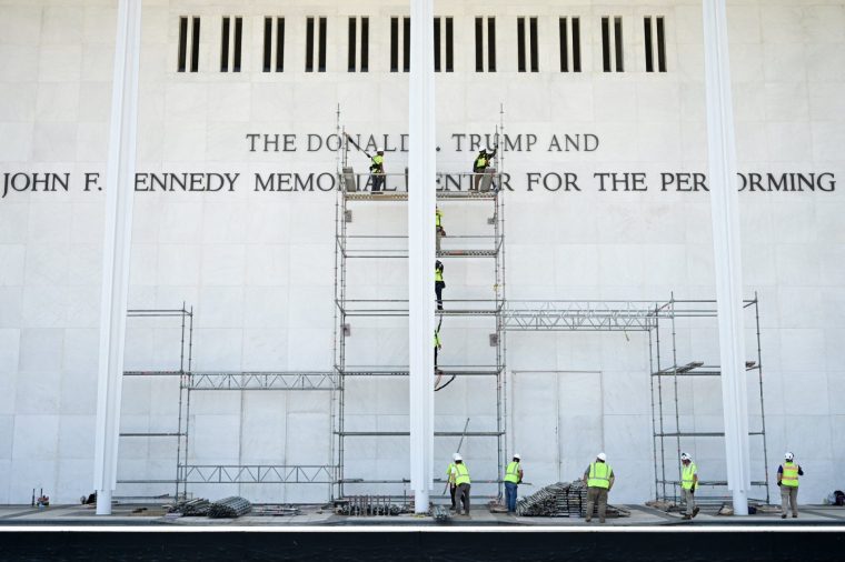 TOPSHOT - Workers stand on scaffolding near the signage for the Donald J. Trump and John F. Kennedy Memorial Center for the Performing Arts in Washington, DC, on June 12, 2026. A US federal judge on Friday rejected a bid by the board of the Kennedy Center and the Justice Department to halt the removal of President Donald Trump's name from the performing arts venue. District Judge Christopher Cooper, in a ruling last month, ordered Trump's name taken off the iconic building in the nation's capital by Friday, June 12, 2026. (Photo by Alex WROBLEWSKI / AFP via Getty Images)