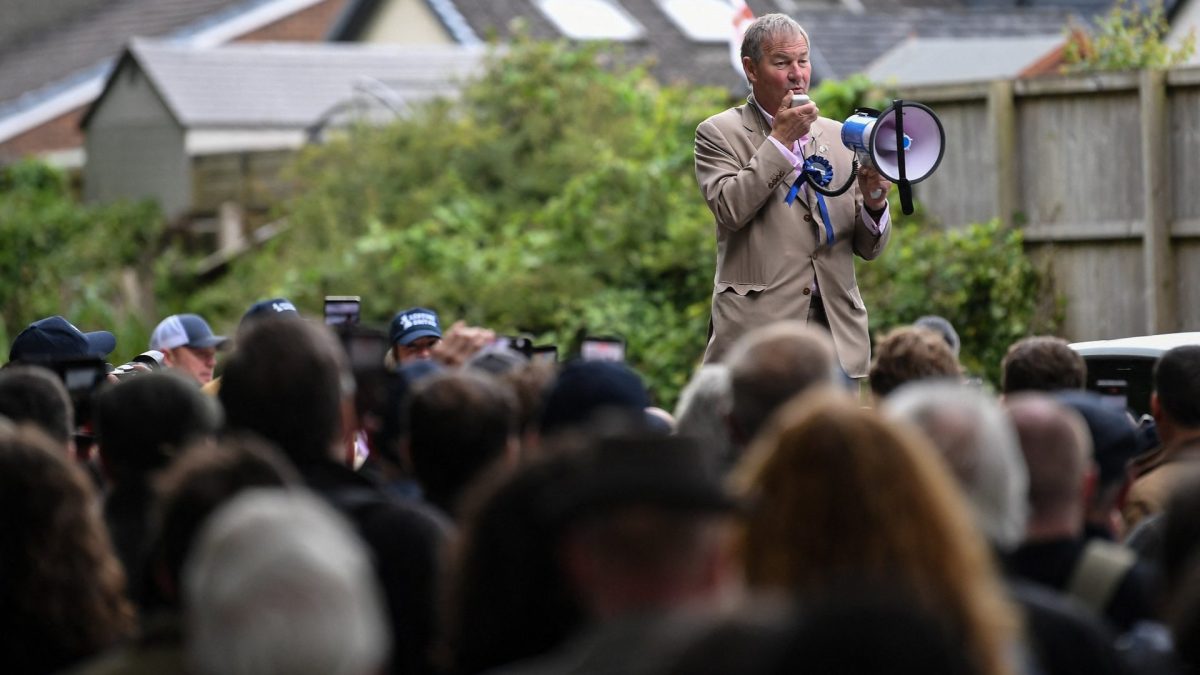 Restore Britain leader Rupert Lowe (R) speaks to people as they campaign ahead of the Makerfield by-election on June 18, west of Manchester, north-west England on June 13, 2026. (Photo by PETER POWELL / AFP via Getty Images)
