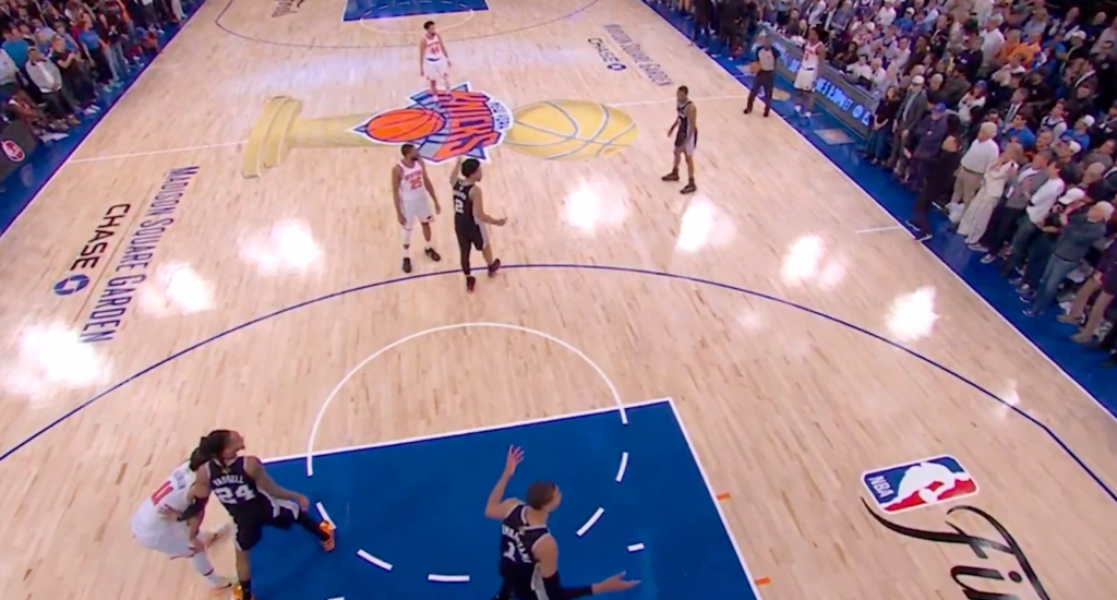 An overhead shot of a basketball game, showing players from the Spurs and another team on the court.