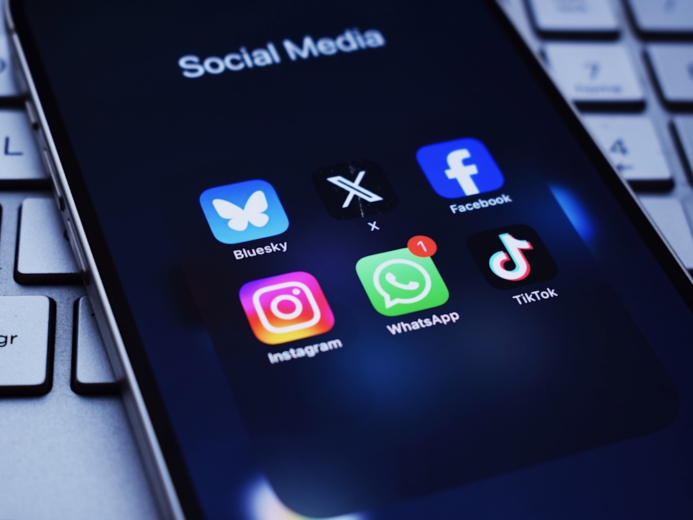 A smartphone screen shows logos for a number of social media apps, including Instagram, X and TikTok.