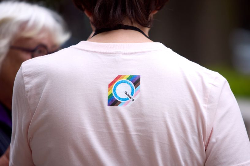 Man wearing white t-shirt with rainbow Q on back