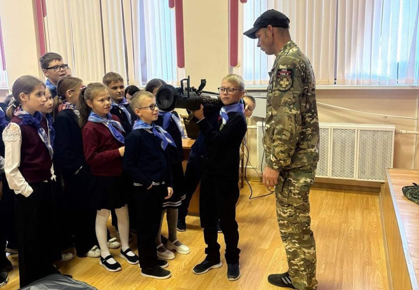 A Russian soldier instructs schoolchildren on holding a shoulder-launched munition. ti71.ru