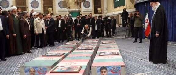 Iranian slain Supreme Leader Ali Khamenei stands before coffins draped in Iranian flags during a memorial ceremony for military commanders and officials killed in the Iran-Israel conflict, in Tehran.