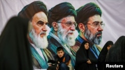 People gather near a banner of Iran's late leader of the Islamic Revolution Ayatollah Ruhollah Khomeini, Iran's late Supreme Leader Ayatollah Ali Khamenei, and Iran's current Supreme Leader Mojtaba Khamenei, on the day of a ceremony for the 37th anniversary of the death of Ayatollah Ruhollah Khomeini at Khomeini's shrine in southern Tehran, Iran June 4, 2026.