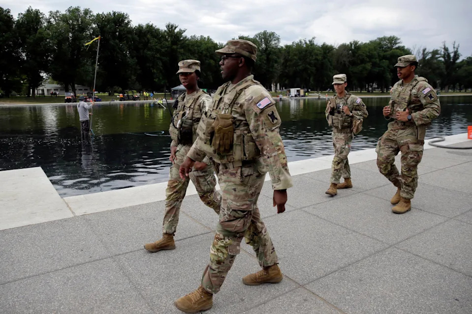 Members of the National Guard patrol as National Park Service workers clean algae from the Lincoln Memorial Reflecting Pool in Washington, Thursday, June 18, 2026. 