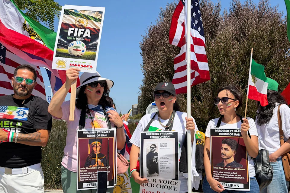 People wave US and pre-revolutionary Iranian flags as they protest the Iranian regime outside of Los Angeles Stadium (temporarly renamed from SoFi Stadium) in Inglewood, California, on June 7, 2026, ahead of the start of the 2026 FIFA World Cup. Iran are scheduled to open their Group G campaign against New Zealand in Los Angeles on June 15, before facing Belgium in the same city and then Egypt in Seattle. (Photo by Sarah LAI / AFP via Getty Images)