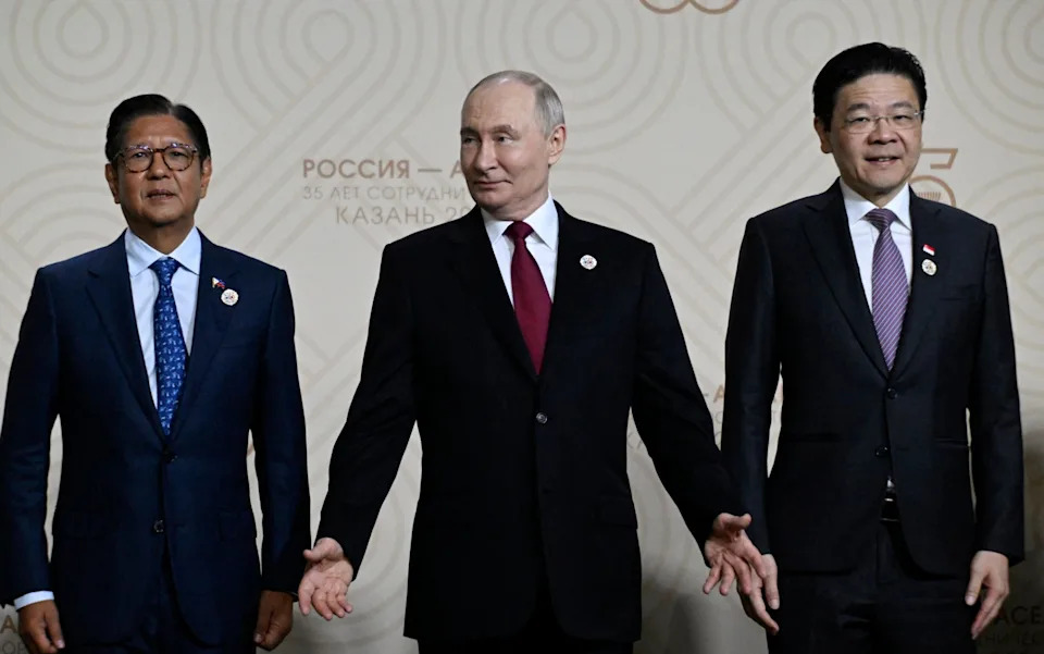 Vladimir Putin gestures next to Philippine President Ferdinand Marcos Jr. and Singapore's Prime Minister Lawrence Wong during a family photo of the Russia-ASEAN summit in Kazan