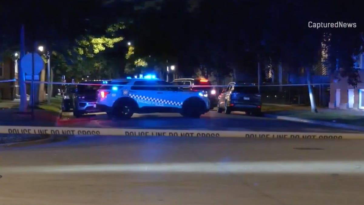 image shows police crime scene tape with a police vehicle