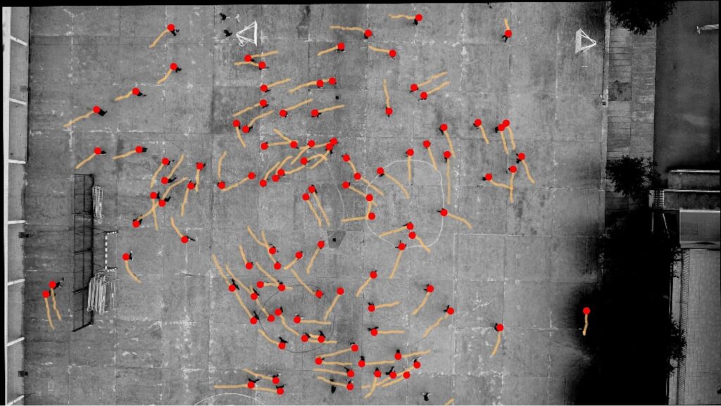 Top down image of an open paved area and the motions of people walking in the area as indicated by dots and lines