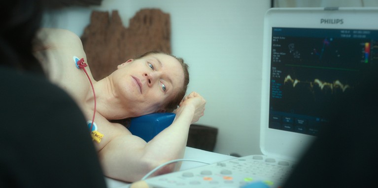 A film still showing Bryan Johnson lying on an examination table, hooked up to a heart monitor.