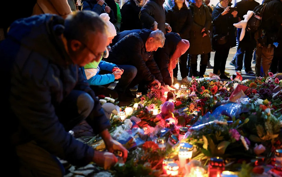 People leave candles and floral tributes to the victims near the site where a car rammed into a crowd at a Magdeburg Christmas market