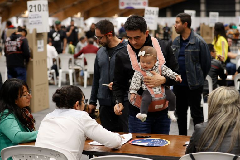 epa13007654 Electoral workers greet voters at a polling station during the presidential election in Bogota, Colombia, 31 May 2026. More than 41 million Colombians are registered to vote. EPA/MAURICIO DUENAS CASTANEDA