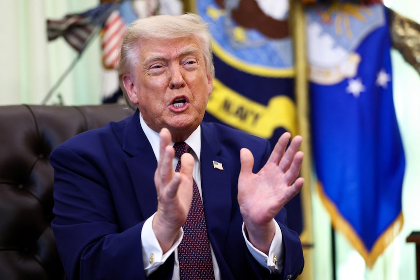 Donald Trump gestures with both hands as he speaks from the Resolute Desk.