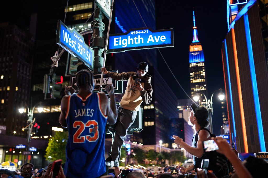 New York Knicks fans climb a street pole to celebrate the team's victory.