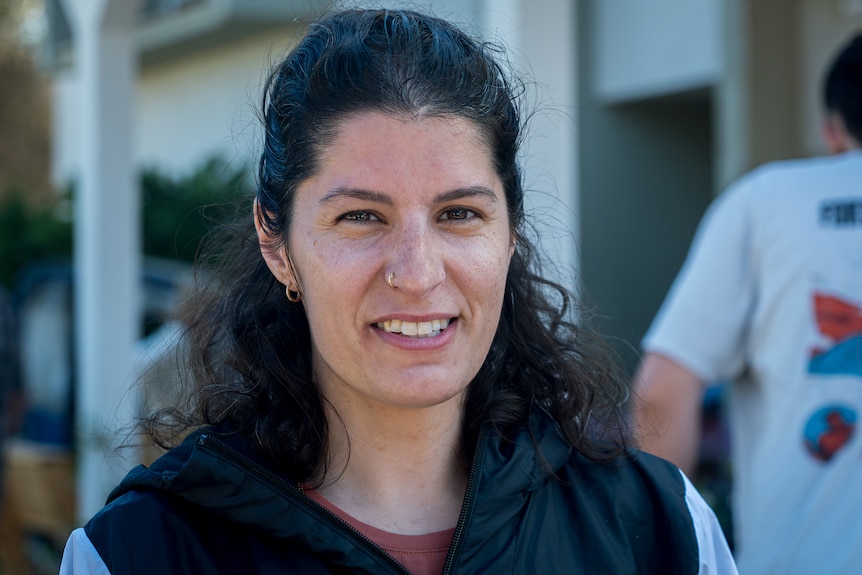 A close up of a woman with black hair smiling.