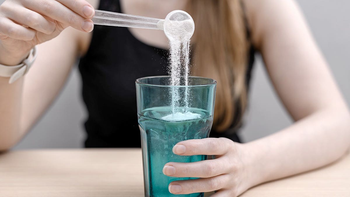 A woman dissolving fish collagen powder in a glass.