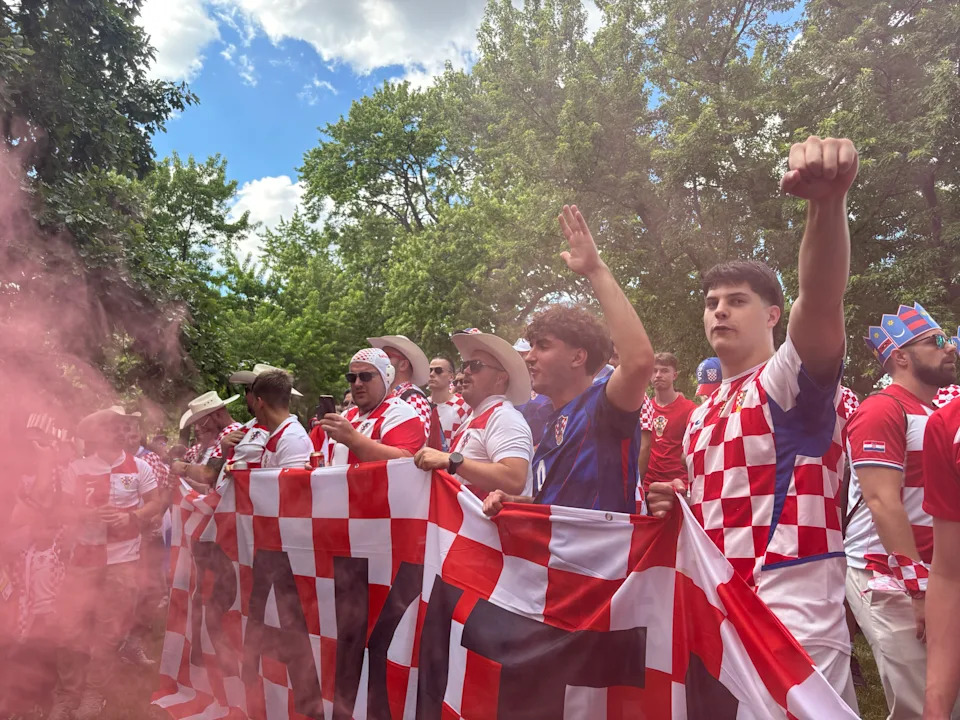 Croatia fans surrounded by red smoke, holding a Croatia flag