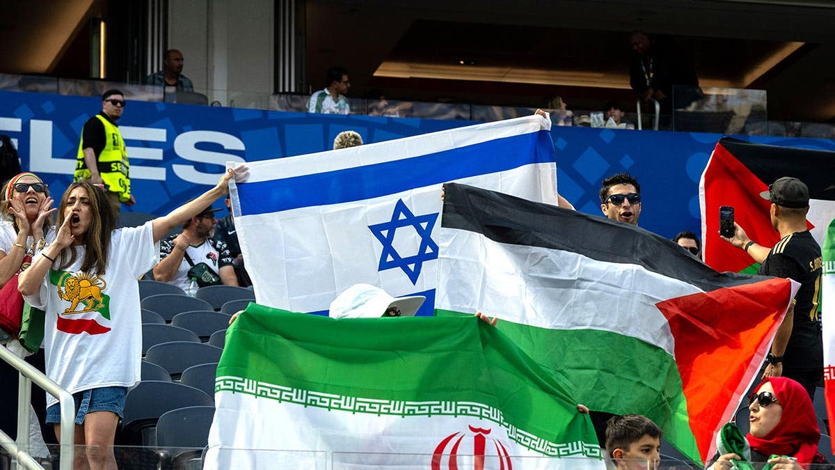 Fans of Iran holding flags of the Islamic Republic of Iran and Israel at Los Angeles Stadium.