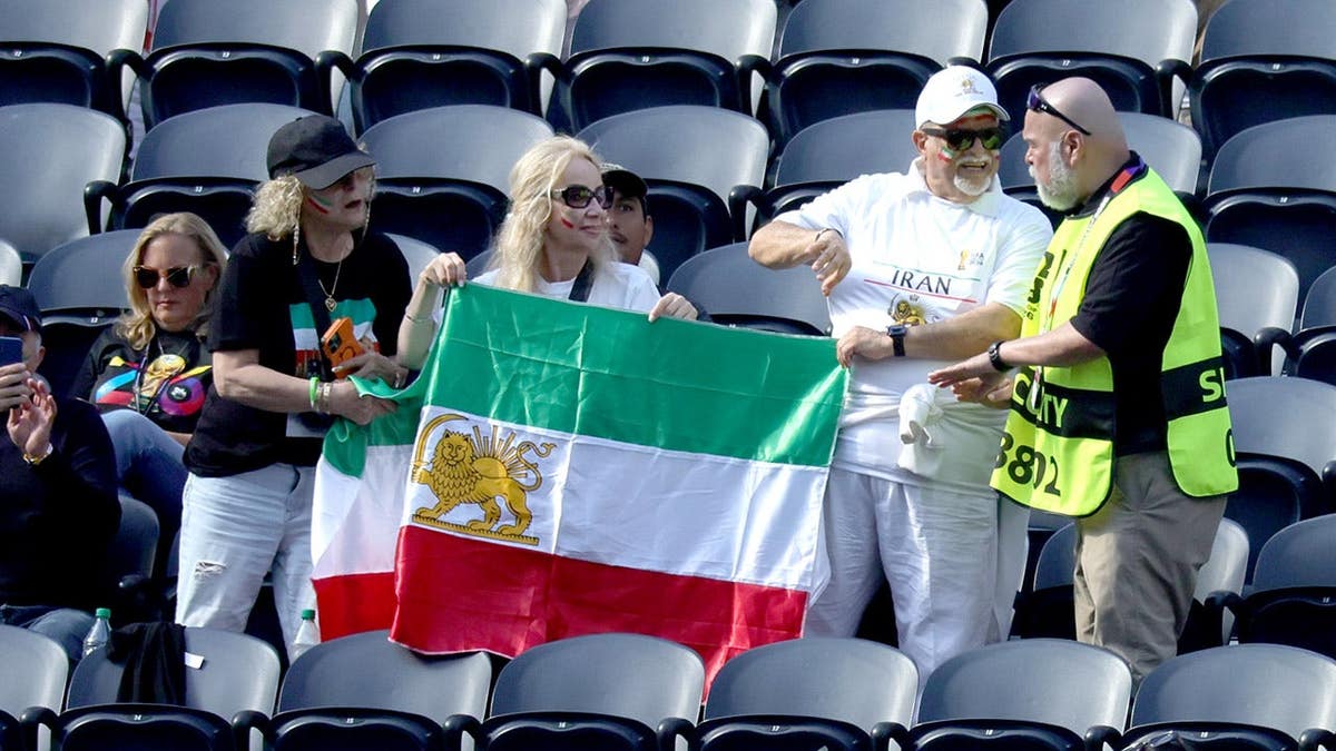 An official talks with people holding pre-revolutionary Iranian flags at SoFi Stadium in Inglewood, California.