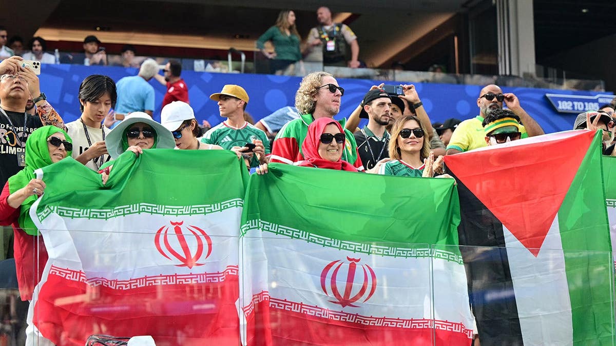 Iranian fans holding Palestinian and Iranian flags at Los Angeles Stadium