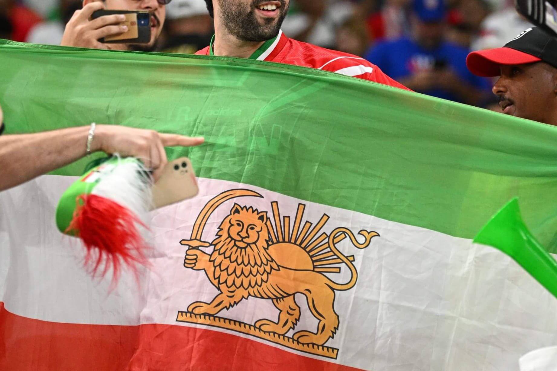 A photo of a man holding the pre-revolutionary Iranian flag