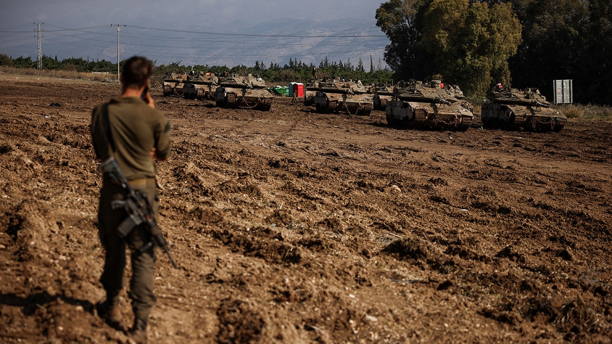 Israeli soldier standing near military vehicles by a road close to the Israel-Lebanon border