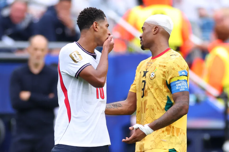 Jude Bellingham covers his mouth whilst speaking to Jordan Ayew