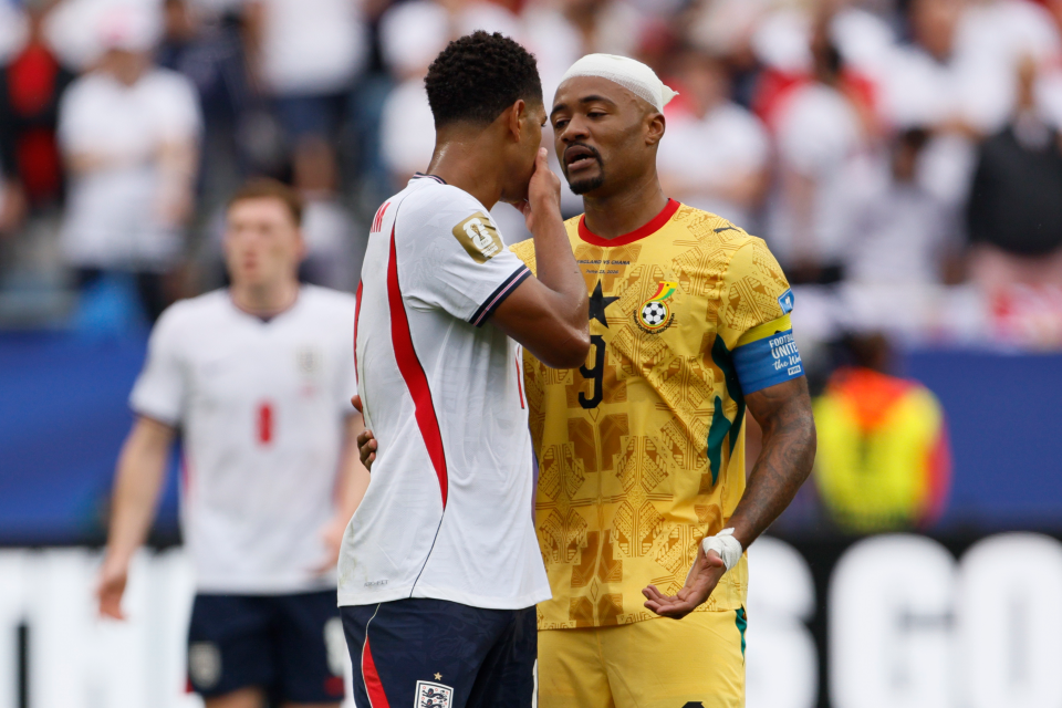 Jude Bellingham covers his mouth whilst speaking to Jordan Ayew