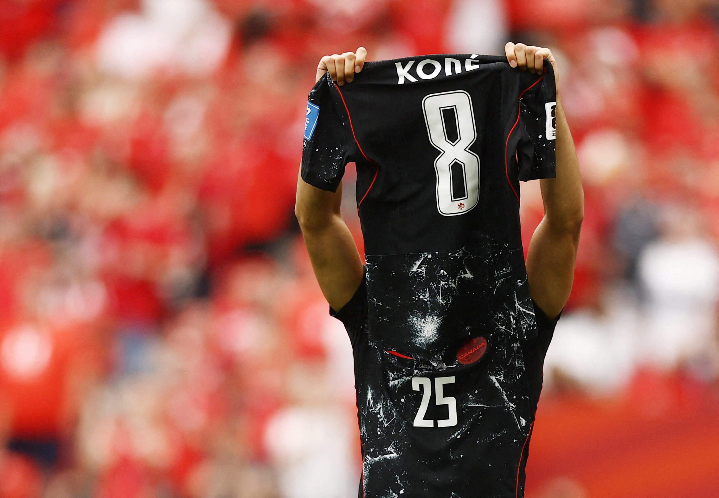 Nathan Saliba holding up Koné's shirt after scoring against Qatar