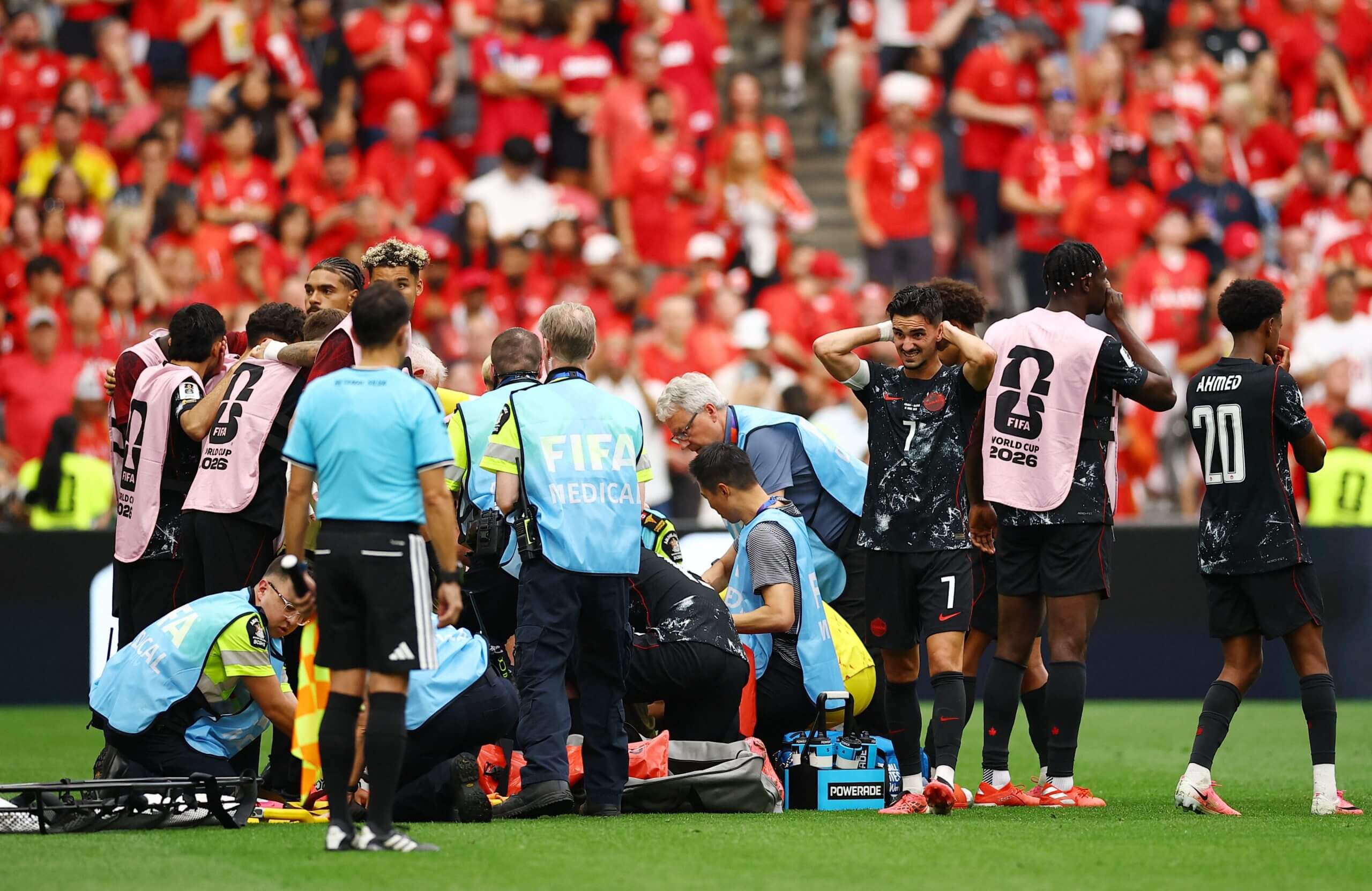 Canada players look distressed while medical staff and players gather around Kone (not visible) on a stretcher