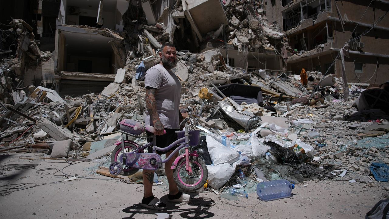 Barber Wissam Srour, 41, holds his daughter's bicycle recovered from his barbershop as he searches for belongings in the rubble of the shop, damaged in an Israeli strike, in the southern port city of Tyre, Lebanon, Friday, June 19, 2026. (AP Photo/Hassan Ammar)